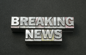 A silver plated song with the words BREAKING NEWS in the middle on top of a black rabbited table.