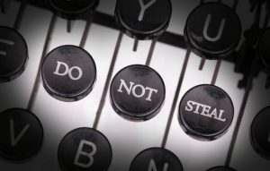 An older model typewriter with three highlighted black keys with white writing stating DO NOT STEAL across the keys.