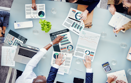 A group of accountants sitting around a table strategizing during a meeting.