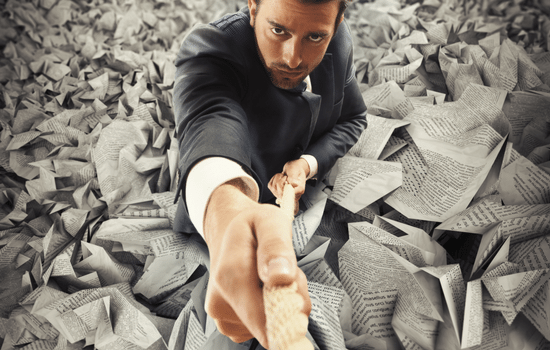 An accountant struggling to climb a rope out of a deep pit of forms and newspapers.