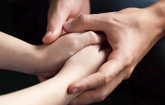 Paid Sick and Family Leave Article_Holding Hands_550x350 Older person holding younger person's hands in support