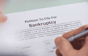 close up of person's hands filling out bankruptcy filing