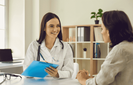 Healthcare professional speaking with a client at a desk.