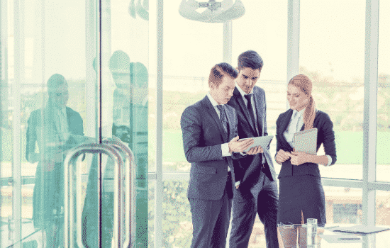 Real estate agent speaking with two coworkers in a corner office.