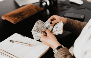 A woman counting a stack of money at a desk.