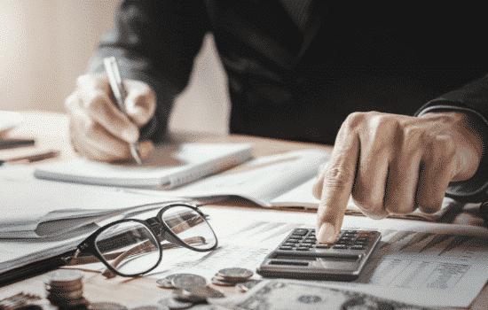 An accountant working on a calculator on financial ledgers.