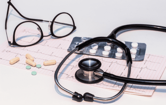 Medical devices with medicines sitting on top of a paper and stethoscope.