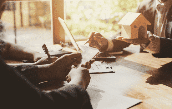 Individuals commencing in real estate planning at a desk.