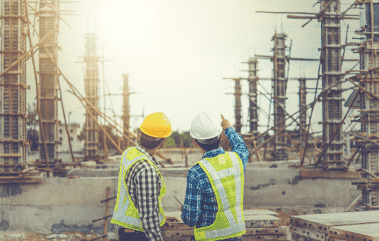 Two foremen at a job site reviewing plans for work to begin.