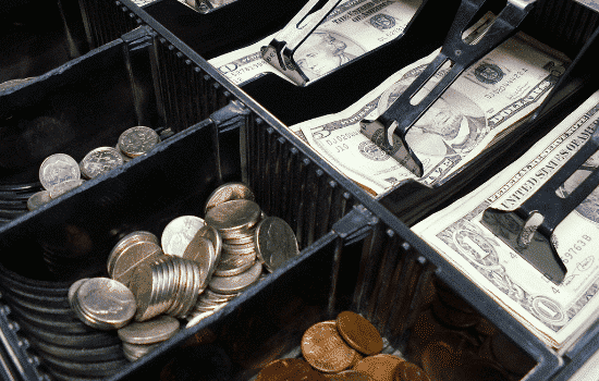 Cash register draw with paper money and coins in it.