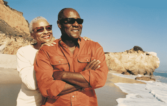 African American couple smiling and enjoy their time on the sandy beach watching the ocean waves roll in.