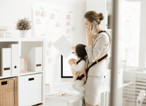 A nanny during COVID working while holding a child in a body carrier.