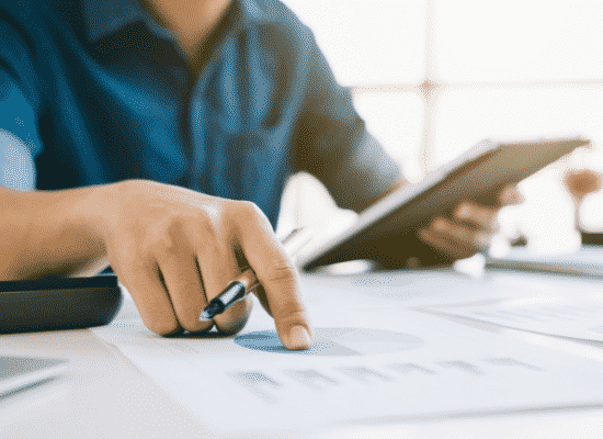 A man working on a pie chart pointing to the paper with a pen in his hand.