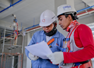 Two construction workers verifying their plans at a job site.