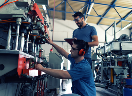 Two mechanics working on a manufacturing plant's conveyer system.