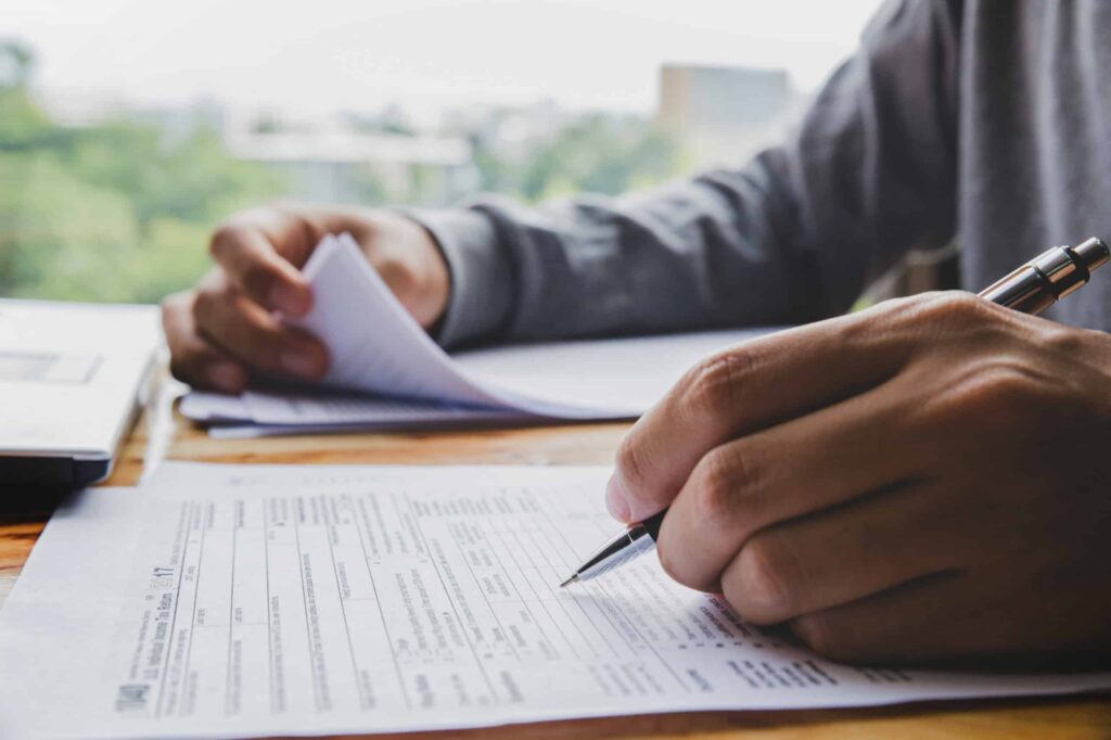 An accountant filling out Form 5472 at his desk. The accountant is left handed.