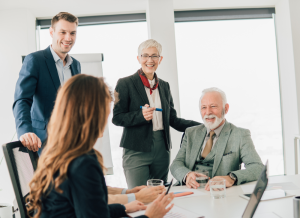 People of different ages are at a table in a business office setting.