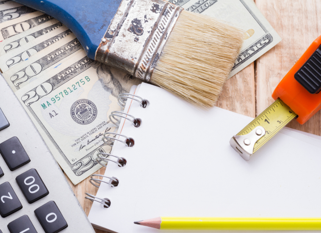 A notebook, calculator, and tools on a wooden background with cash.