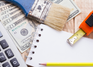 A notebook, calculator, and tools on a wooden background with cash.