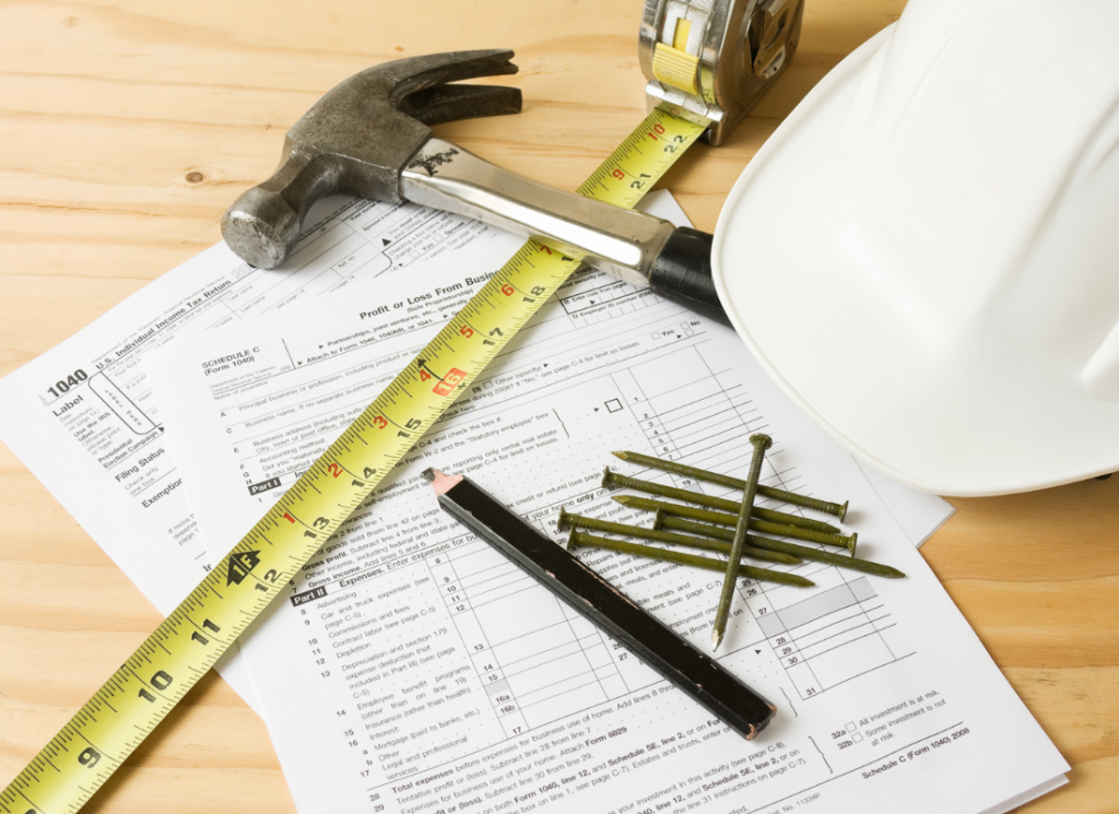 A hardhat and construction tools sitting on top of tax forms.