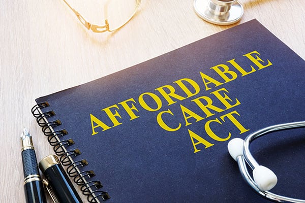 A blue spiral notebook with the text of "Affordable Care Act" printed across it in yellow.