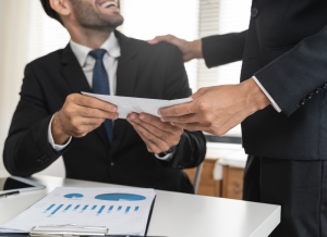 A close up view of an office worker receiving their salary from their boss.