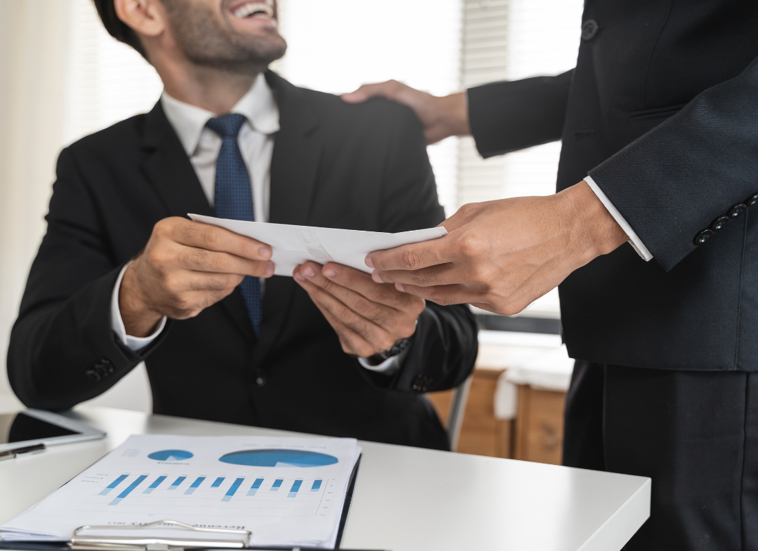 Establishing Pay Transparency featured image A close up view of an office worker receiving their salary from their boss.