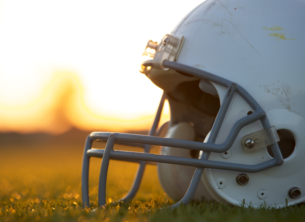 A football helmet is sitting upright on a grass football field.