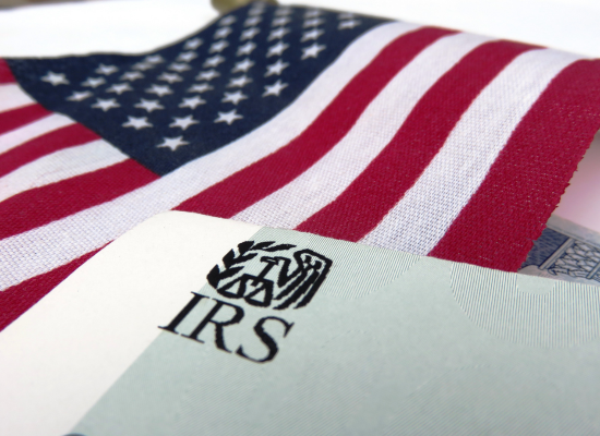 The American flag is shown on a white background. On top of the flag is a document with the IRS letterhead.