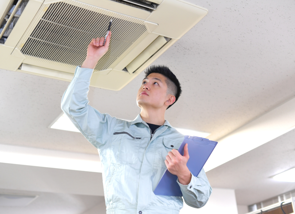 A maintenance worker is inspecting an air conditioner unit in an office building.