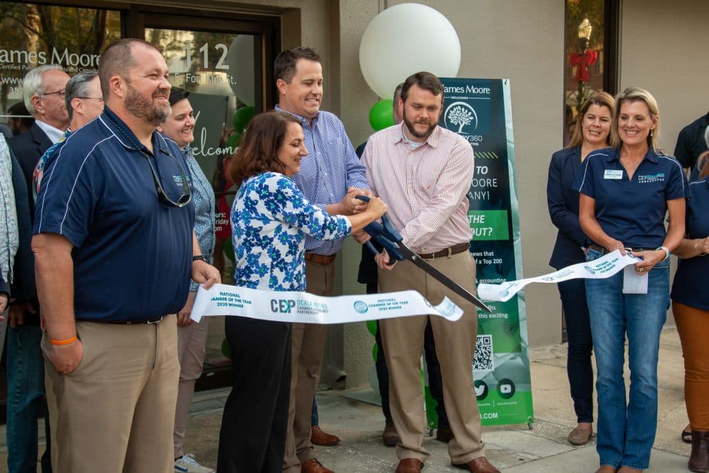 Ribbon cutting ceremony featuring Suzanne Forbes, John Van Dozer, Russell Lindsay and other James Moore Ocala employees.