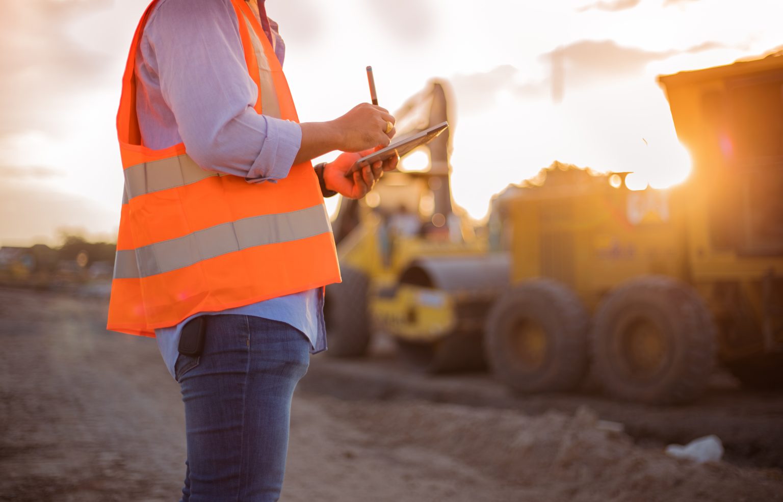 Asian engineer with hardhat using tablet pc computer inspecting Construction worker on a job site.