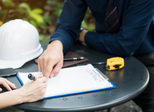 A business owner sitting at a table with a bonding agent and signing a construction bond contract.
