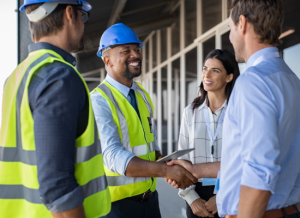 Construction workers shake hands at a job site to secure their construction bonding process..