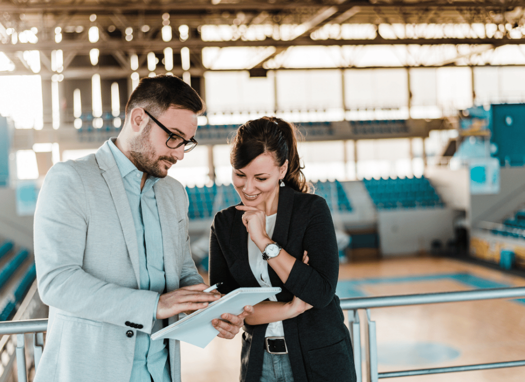 Two sports manager talking about NIL management in a collegiate sports hall.