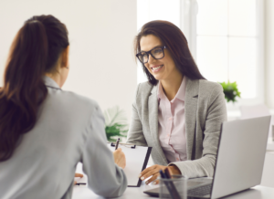 A business professionals signing a contract and sitting at a desk across from a HR professional.