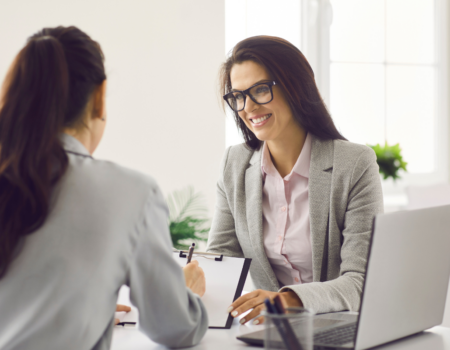 A business professionals signing a contract and sitting at a desk across from a HR professional.