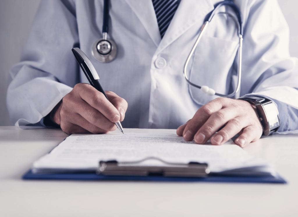 A physician, and independent medical practice owner, is wearing a white doctor's coat and stethoscope while writing notes on a clipboard.