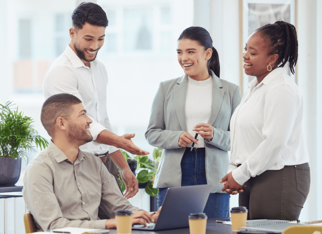 Outsources HR services team collaborating with business clients and laughing while looking at a laptop on the desk in a boardroom.