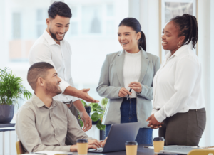 Outsources HR services team collaborating with business clients and laughing while looking at a laptop on the desk in a boardroom.