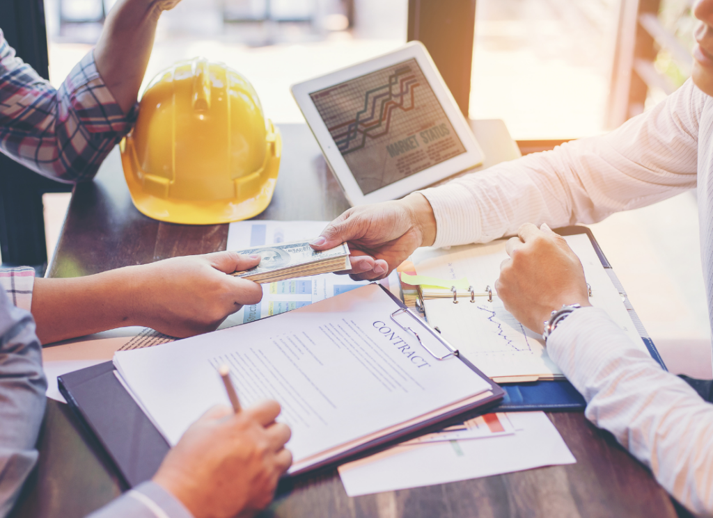 Three people at a construction business meet to discuss a construction contract and working capital.