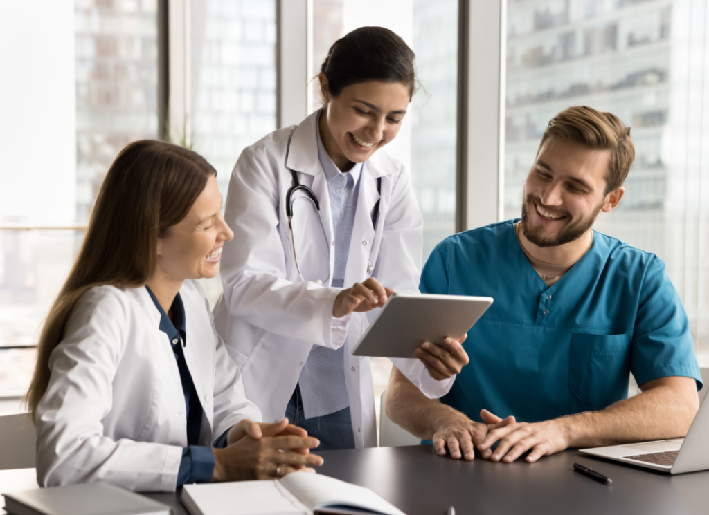 Medical practice owners and colleagues in uniforms are using a tablet computer and discussing their healthcare practice valuation.