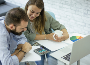 A nonprofit director and nonprofit accountant are siting at a desk with a laptop computer and financial documents.