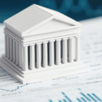A small white model of a government building with columns sits on financial documents featuring charts and graphs, symbolizing outsourced finance in government.