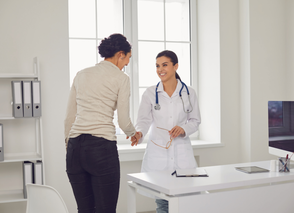 A smiling doctor in a white coat shakes hands with a CPA in a bright medical office, highlighting the value of CPA guidance when starting a new medical practice.