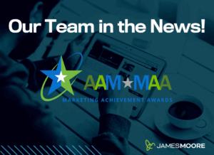The AAM Marketing Achievement Awards logo on a background that shows a person using a tablet with a coffee cup nearby, and large white text reads “Our Team in the News!” with the James Moore logo in the corner.