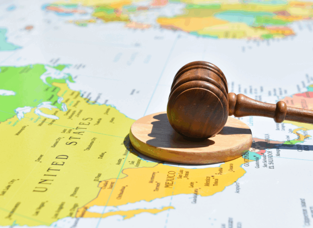 A wooden judge’s gavel rests on a world map centered on the United States and Mexico, symbolizing the global legal and regulatory impact of international tax provisions.