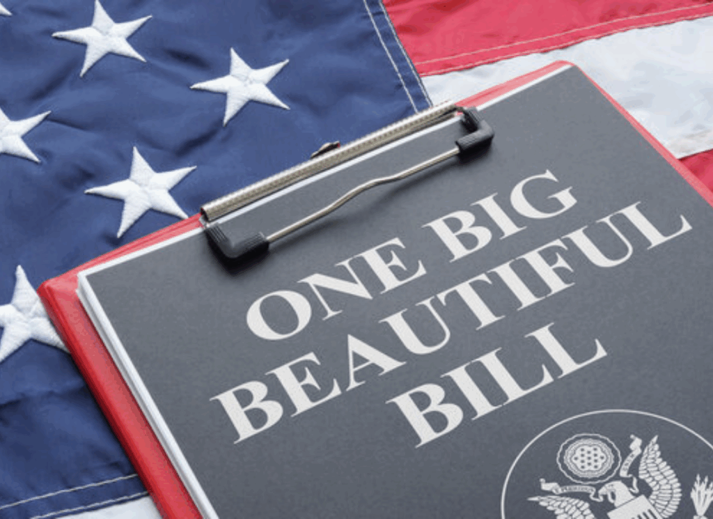 A clipboard labeled "One Big Beautiful Bill" rests on an American flag, symbolizing recent U.S. legislation and its potential impact on nonprofit organizations.