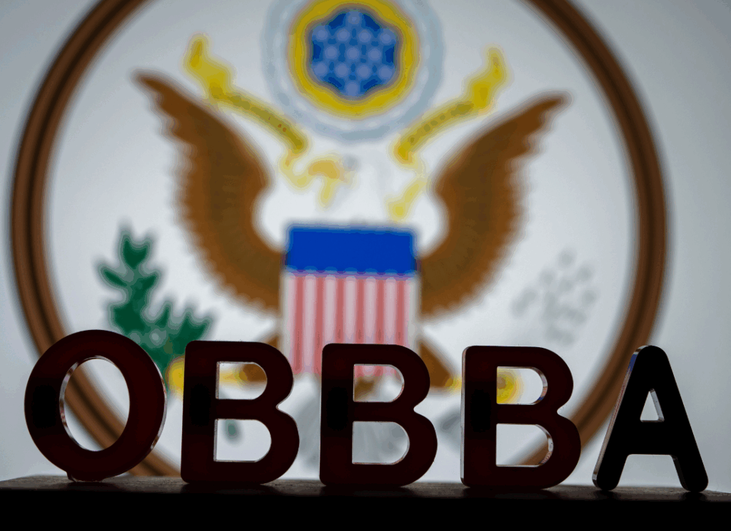 Block letters spelling "OBBBA" sit in front of a blurred U.S. government seal, symbolizing the impact of the One Big Beautiful Bill Act on higher education institutions.