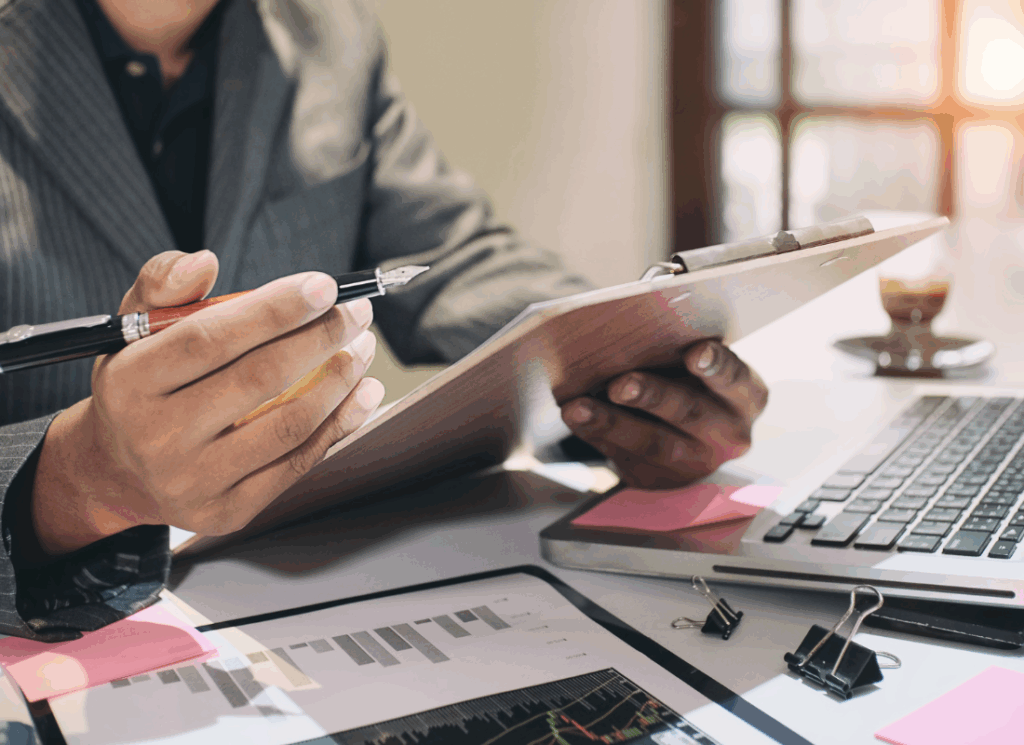 A person in a business suit reviews financial charts and notes on a clipboard at a desk with a laptop, illustrating the importance of nonprofit audit readiness and preparation.
